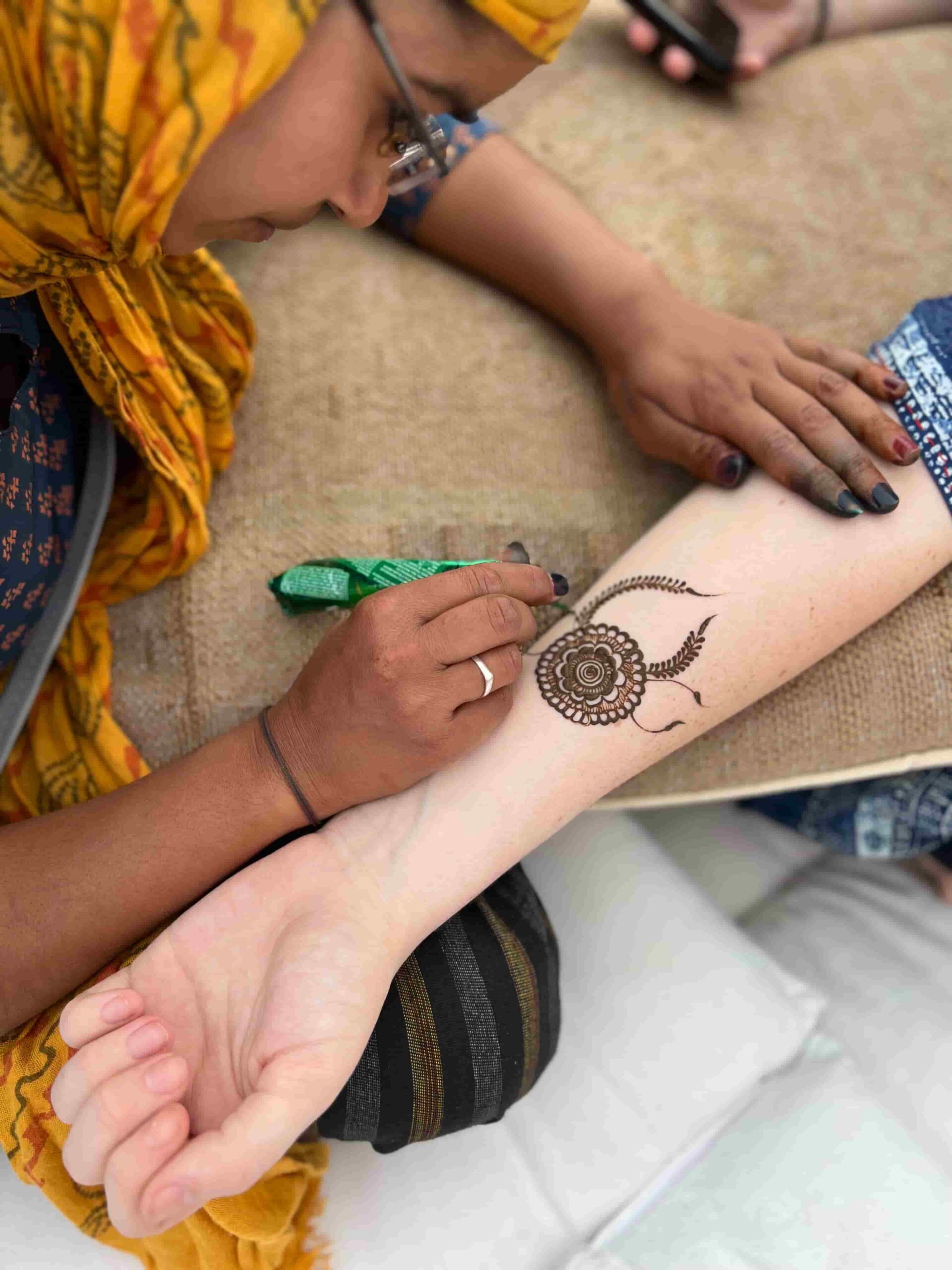 lady doing henna deisgn on arm of guest