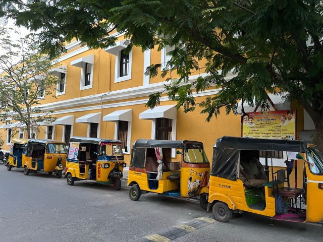 row of yellow tuk-tuks in front of yellow building in Pondicherry