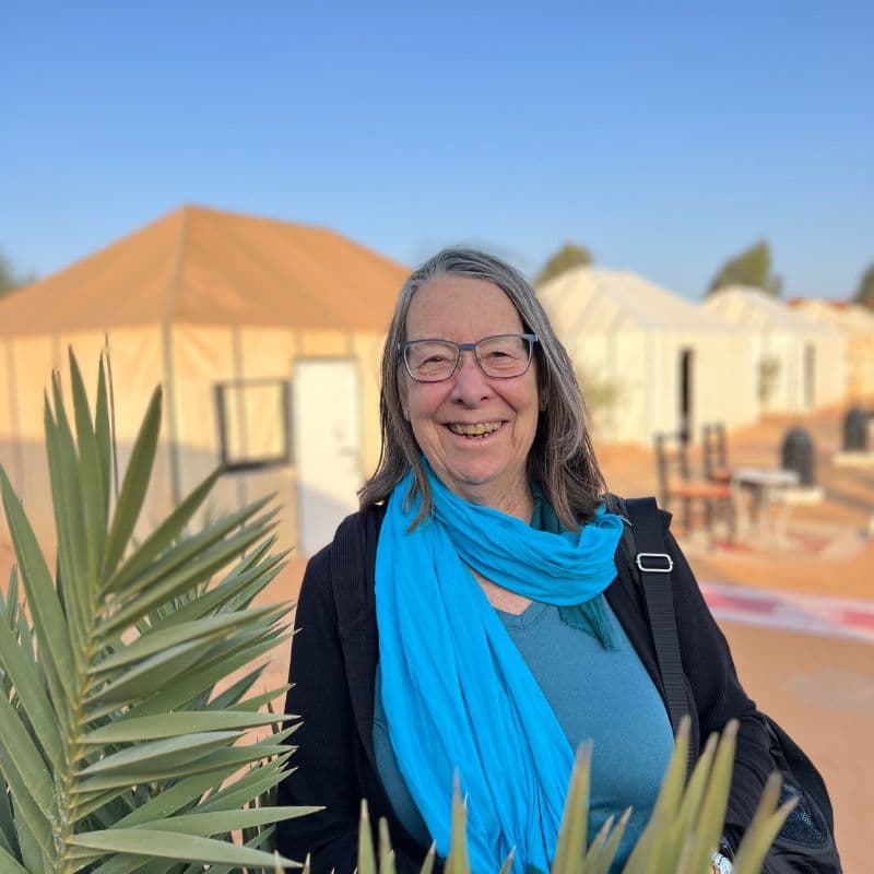 lady with blue scarf standing in front of glamping tent in Sahara
