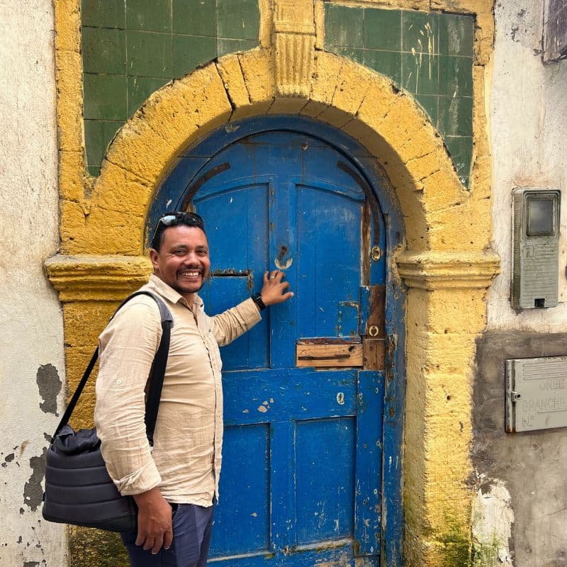 Moroccan man standing in front of blue door