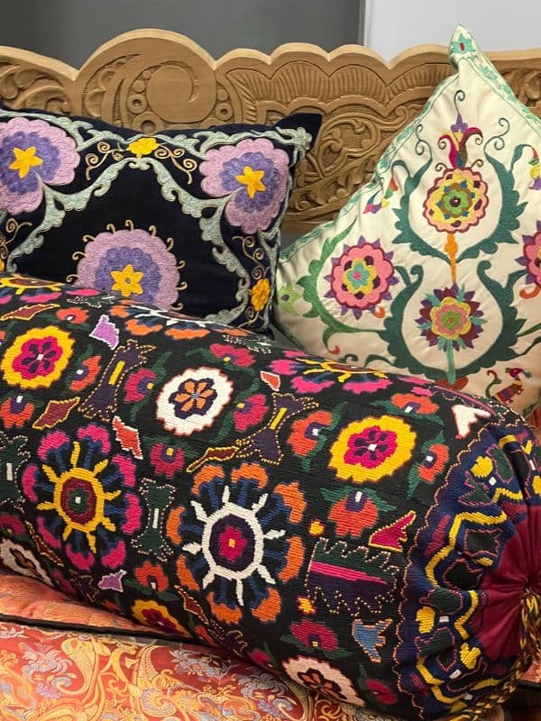 three embroidered cushions on wooden day bed in Uzbekistan