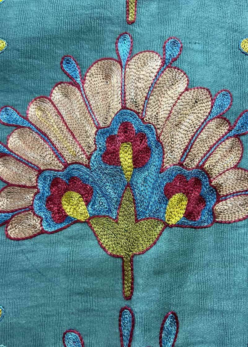 close up image of embroidered flower on turquoise background
