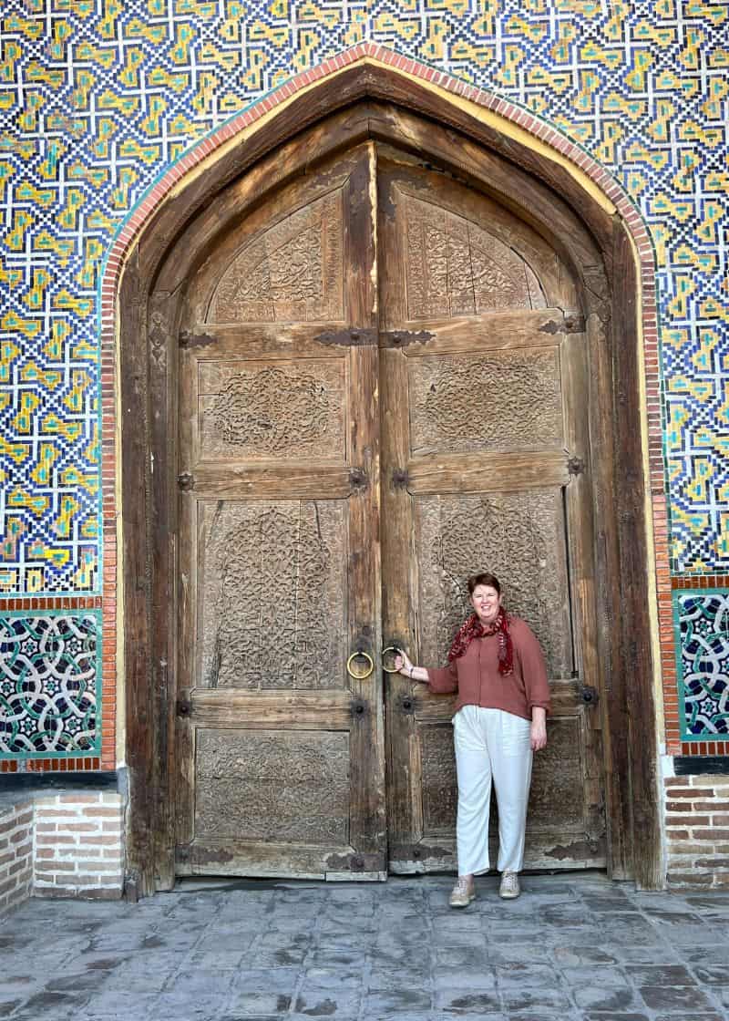 lady standing in front of large wooden door with tiles decorative edge