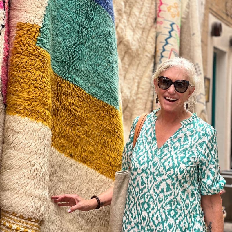 lady standing next to Moroccan rug hanging on wall