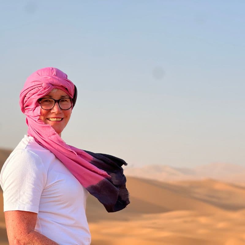 lady with pink scarf on her head with Sahara sand dunes in background