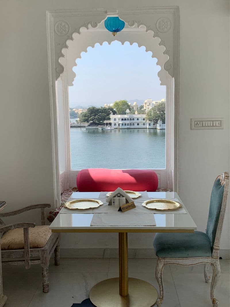 table for 2 in front of window seat with lake in background